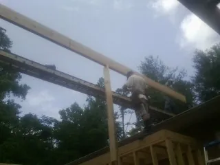 Carpenter setting a ridge beam over a new addition frame — Ice Dam Removal by Roofing Brothers in Clearville