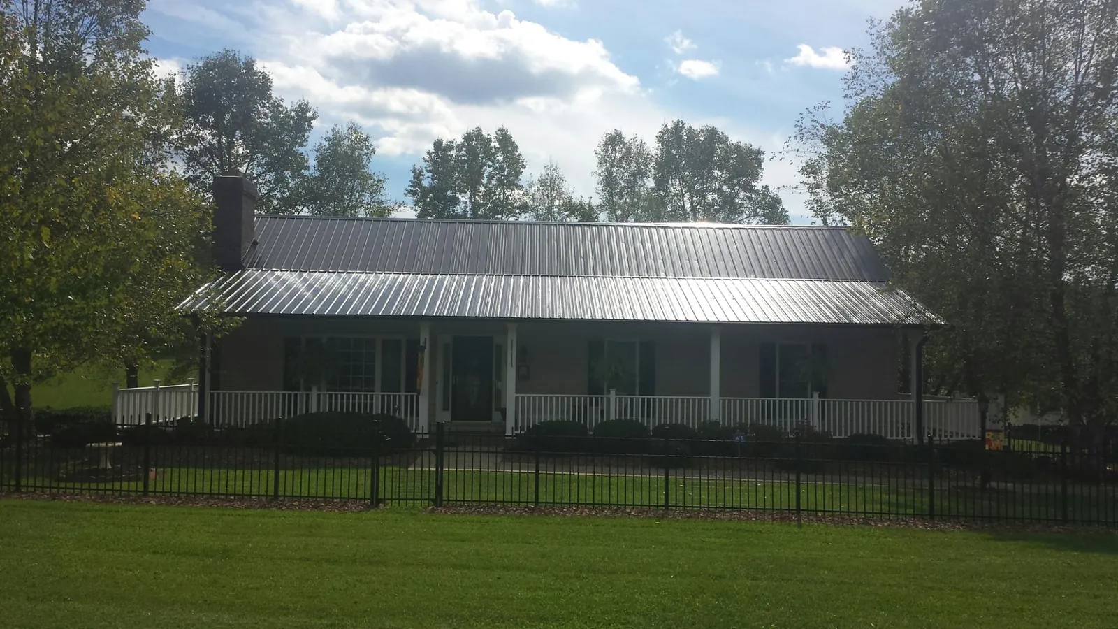 Gray metal roof on a brick ranch with a full width front porch — Gutter Guard Installation work by our crew in Clearville