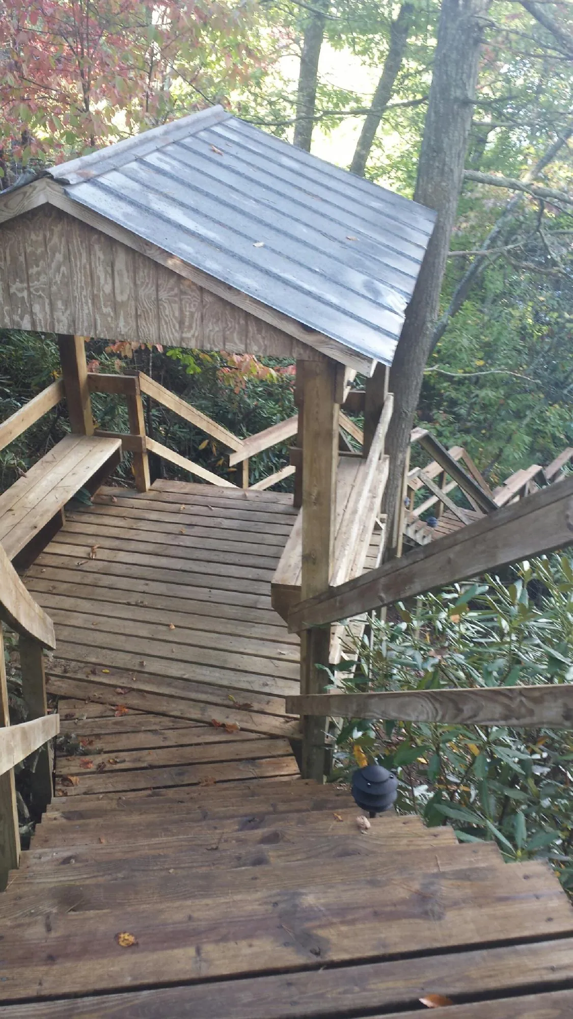 Metal roofed shelter over wooden steps on a wooded walkway — Skylight Repair & Installation work by our crew in Clearville