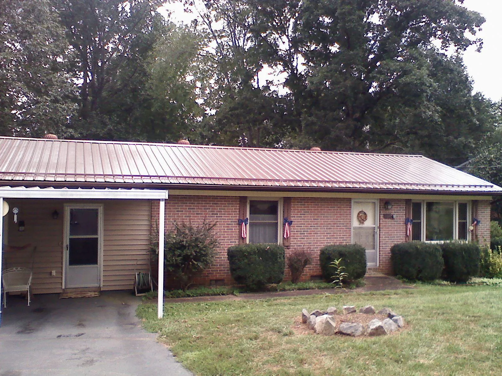 Bronze metal roof and carport on a brick ranch home — Roof Repair work by our crew in Clearville