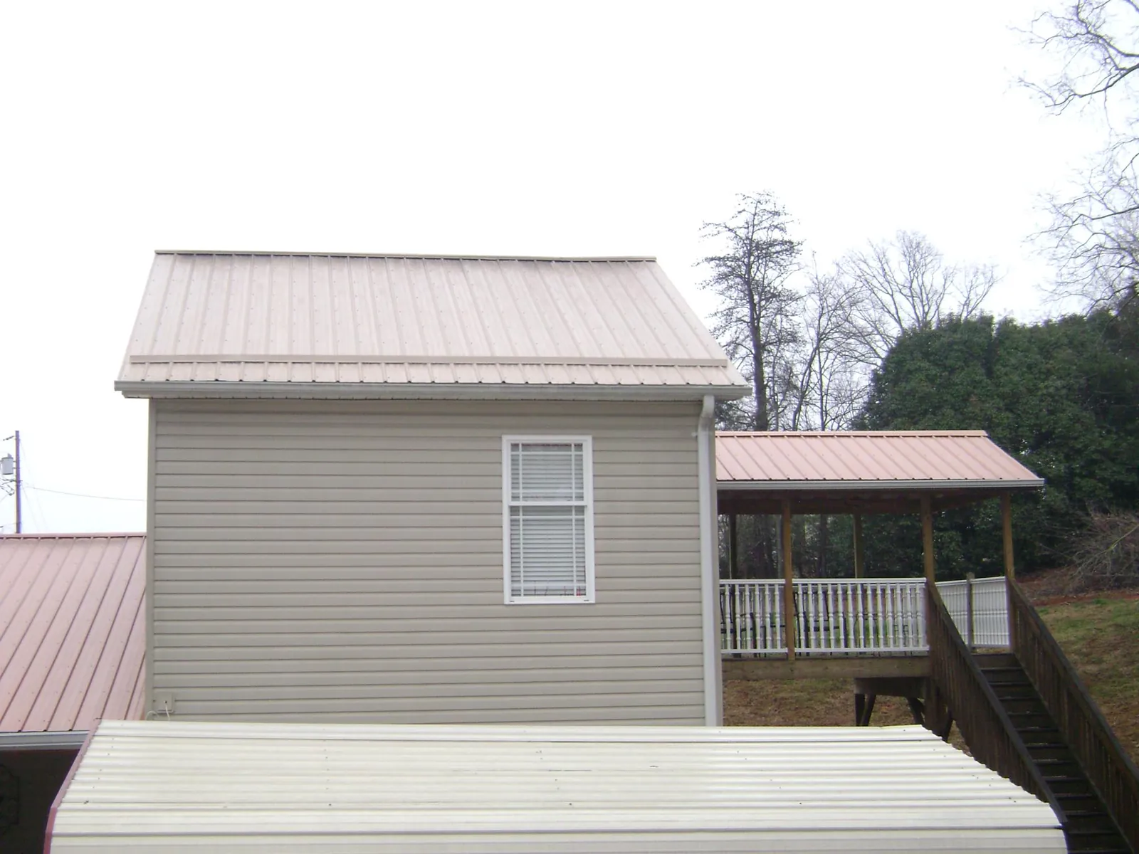 Tan metal roofs on a two story addition and attached porch, from a Roof Replacement job in Clearville