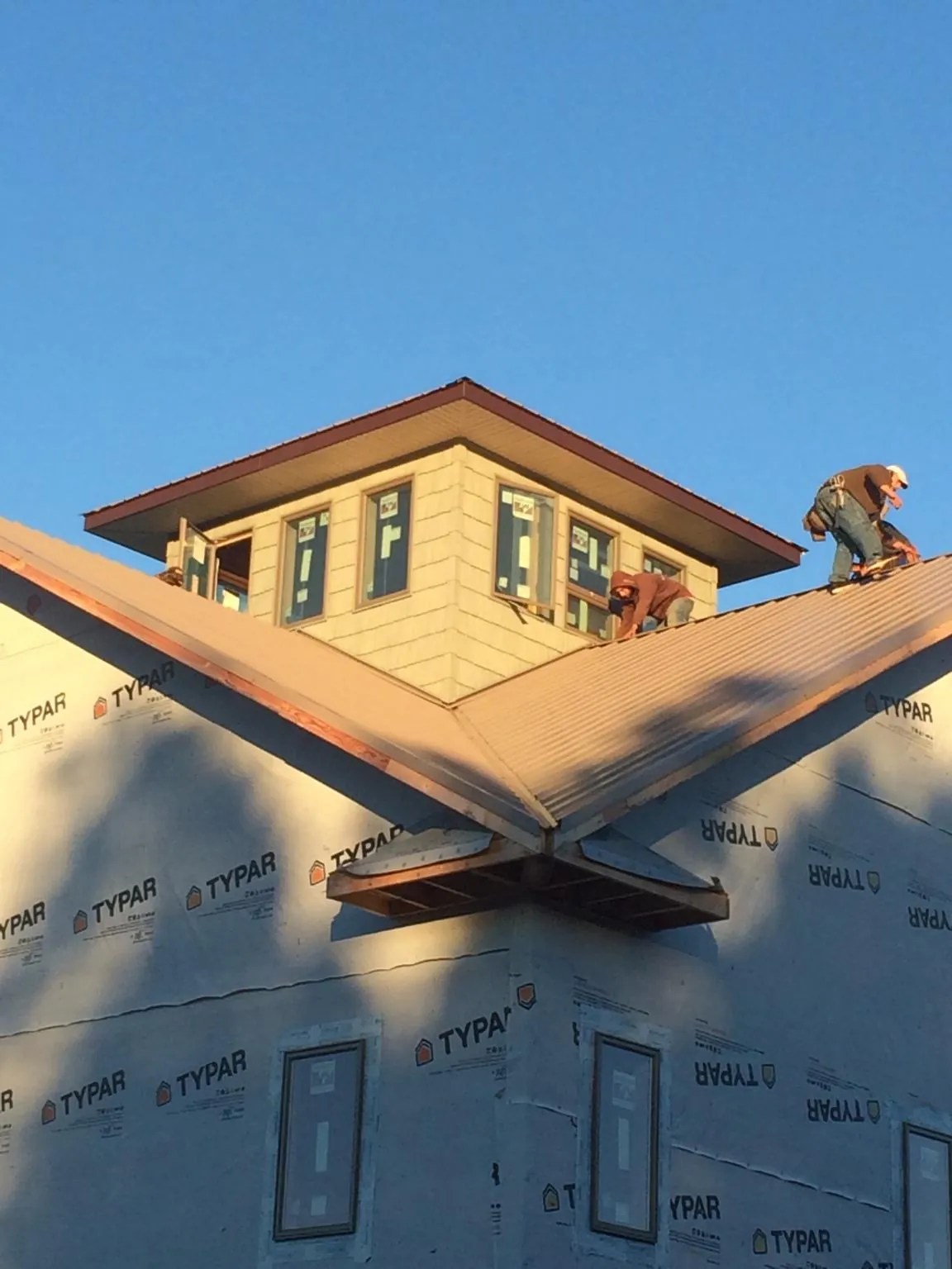 Roofers working around a rooftop cupola on a new metal roof at sunset — Roof Waterproofing in Clearville by Roofing Brothers